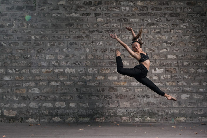 danseuse qui saute devant un mur de pierre vers la gare de bercy