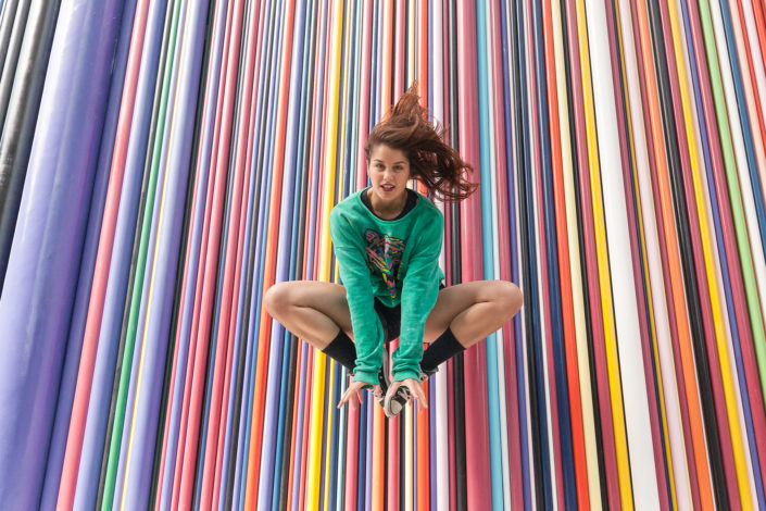 danseuse effectuant un saut devant un mur multicoloré à la défense en France