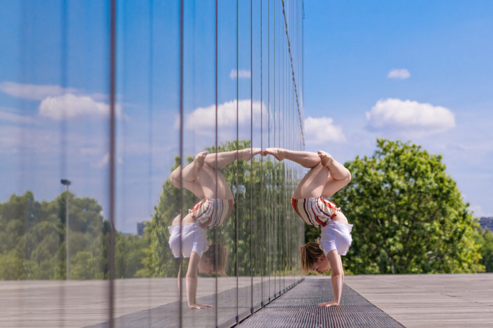 gymnaste lyonnaise effectuant un handstand contre une baie vitree de birhakeim