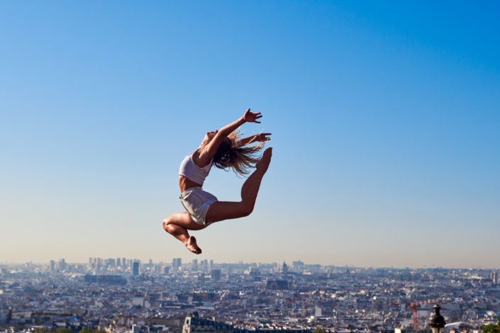 Danseuse contemporain qui effectue un saut devant le sacré coeur à montmartre à paris